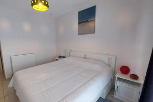 a white bedroom with a white bed and two tables at Botticelli in Koksijde
