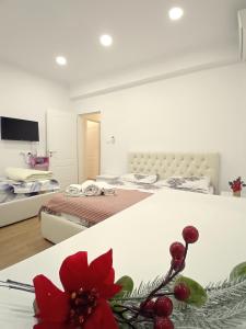 Serendipity Apartment في تيرانا: غرفة بها سريرين وطاولة مزينة بالزهور الحمراء