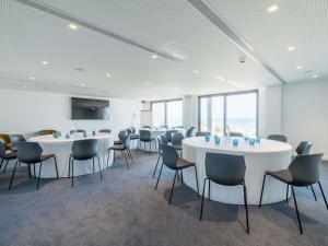 a room with white tables and chairs and windows at Mercure Larnaca Beach Resort in Larnaka +124 photos
