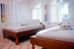deux lits jumeaux dans une chambre avec fenêtres dans l'établissement Mudi House, à Jambiani