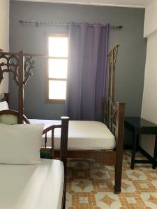 a bedroom with two beds and a window and a table at Vuga Hostel in Zanzibar City