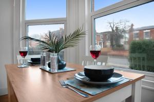 a table with two glasses of red wine and a window at WhiskAwayHomes - St Stephens Court - Apartment 2 in Henwick