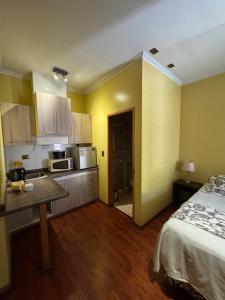 a room with a bed and a kitchen with a microwave at Apart Hotel Uman in Concepción