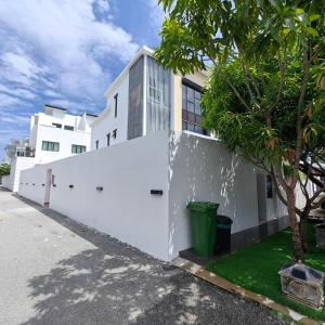 a white building with a white fence and a tree at VnV DORM HOMESTAY in Shah Alam