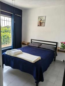 Un dormitorio con una cama con sábanas azules y una ventana. en Casa en Residencial 2 ríos 4 camas 3 habitaciones, en Dos Ríos