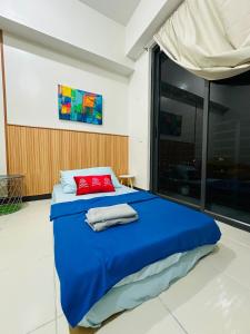 1 dormitorio con cama azul y almohada roja en Semi Furnished Condo at Sta Rosa Zadia Tower 2, en Sampong