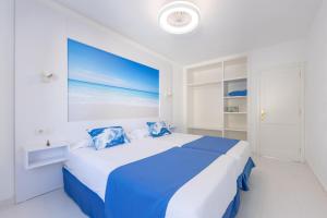 a white bedroom with a blue and white bed at Apartamentos Orly Club Arena Dorada in Puerto del Carmen +25 photos