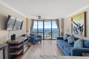 ein Wohnzimmer mit einer blauen Couch und einem Fernseher in der Unterkunft Meridian Plaza 1401 in Myrtle Beach