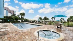 einen Pool mit Sonnenschirm, Tischen und Stühlen in der Unterkunft Meridian Plaza 1401 in Myrtle Beach