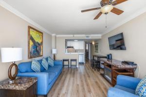 ein Wohnzimmer mit einem blauen Sofa und einem Deckenventilator in der Unterkunft Meridian Plaza 1401 in Myrtle Beach