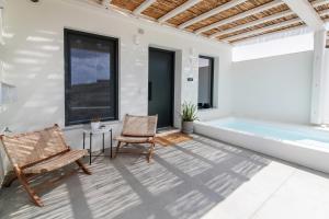 a patio with two chairs and a tub at Rockaine Suites Sunset in Agios Fokas