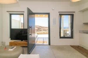 a living room with a sliding glass door and a couch at Rockaine Suites Sunset in Agios Fokas