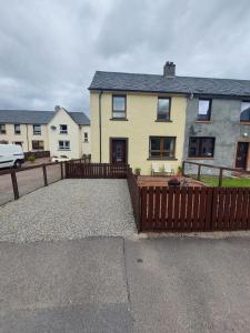 een groot geel huis met een houten hek bij 1 Carn Dearg in Fort William