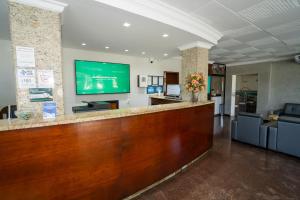 Bandeirantes Hotel في كويابا: ردهة مع بار وتلفزيون على الحائط