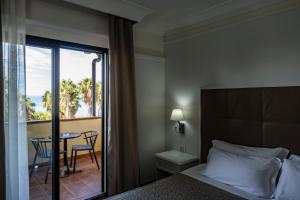 a bedroom with a bed and a balcony with a table at Baia Di Ulisse Wellness & Spa in San Leone +116 photos