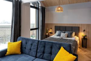 a bedroom with a bed and a couch with yellow pillows at Apartamenty RIO Oława in Oława