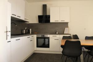 Zimmer im Zentrum mit drei Einzelbetten في بادربورن: مطبخ بخزائن بيضاء وطاولة خشبية