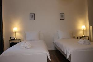 Zimmer im Zentrum mit drei Einzelbetten في بادربورن: سريرين بيض في غرفة بها مصباحين +صورتان