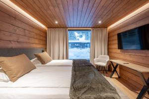 a bedroom with two beds and a desk and a television at Wilderness Hotel Kieppi in Saariselka +51 photos