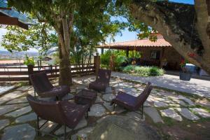 a group of chairs sitting on a patio under a tree at Monte Castelo Flat Temporada in Gravatá