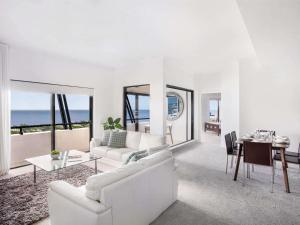 a white living room with a white couch and a table at Mantra Esplanade in Cairns