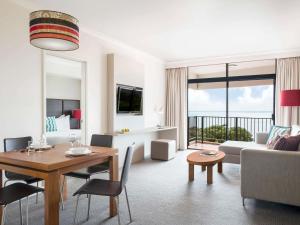 a living room with a table and a living room with a couch at Mantra on The Esplanade in Darwin