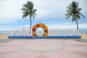 a sign at the beach with two palm trees at Marinas Flat 420 in João Pessoa +1 photo