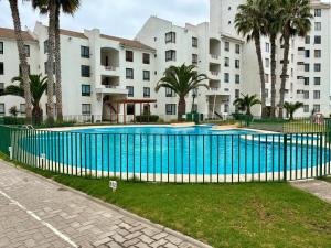 a blue fence around a swimming pool in front of a building at Departamento Borde Mar in Coquimbo
