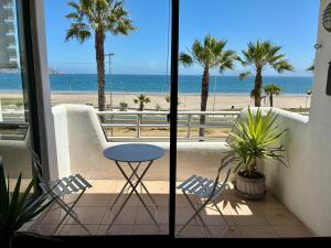 Departamento Borde Mar في كوكيمبو: شرفة مع طاولة وكراسي وشاطئ