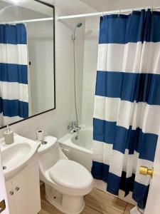 Departamento Borde Mar في كوكيمبو: حمام به مرحاض أبيض وستارة دش زرقاء وبيضاء +13 صورة