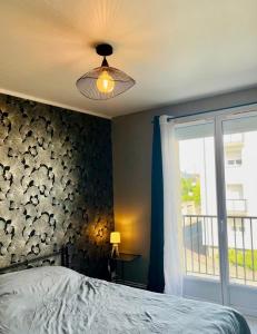 Un dormitorio con una cama con ventilador de techo y una ventana. en Charmant T3 à Angers - parking gratuit, en Angers