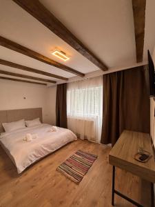 ein Schlafzimmer mit einem weißen Bett und einem Tisch in der Unterkunft La Costel Rânca in Baia de Fier