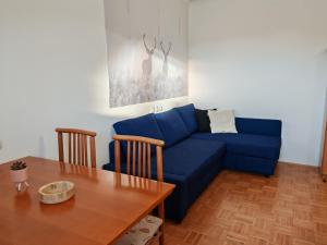 Una sala de estar con un sofá azul y una mesa. en Apartma Roglina, en Zreče