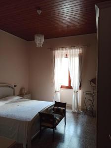 a bedroom with a bed and a chair and a window at Casa Vacanze AnnaLù IUN R5074 in Orosei