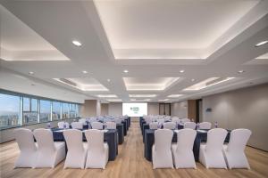 a conference room with rows of chairs and a screen at Holiday Inn Yiwu Center by IHG in Yiwu