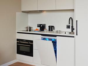 a kitchen with white cabinets and a black oven at Numa Amsterdam Vondelpark in Amsterdam