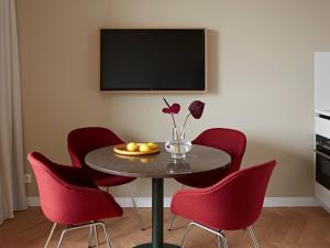 a table with red chairs and a television on a wall at Numa Amsterdam Vondelpark in Amsterdam