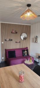 een woonkamer met een paarse bank en een tafel bij Le Petit Clazayéen in Bressuire