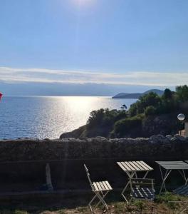 two white chairs sitting next to a body of water at Stone house Anja in Vrbnik