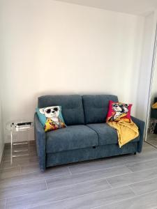 Cap d'Ail - Studio - Terrace with sea view - Malabo في كاب دايل: أريكة زرقاء في غرفة المعيشة مع وسادتين