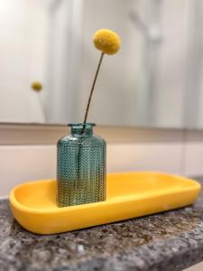 a vase with a flower sitting on a yellow plate at Eldorado Ferienwohnungen in Norddorf