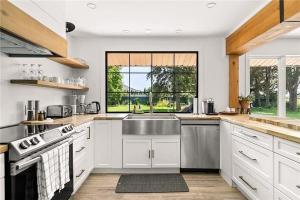 a kitchen with white cabinets and a sink and a window at The County Haus - Indoor Pool & Finnish Sauna in West Lake