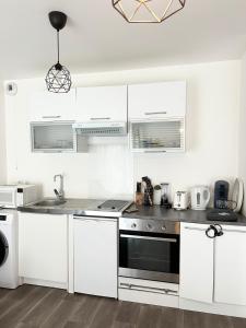 cocina con armarios blancos y fogones negros en Studio moderne à 10 minutes de Paris avec jardin privé, en Romainville