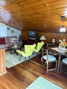 a living room with yellow chairs and a table at Recanto da Vovó in Campos do Jordão