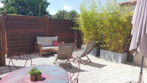 eine Terrasse mit Tisch und Stühlen und einem Zaun in der Unterkunft Maisonnette avec terrasse in Gréoux-les-Bains