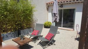 eine Terrasse mit 2 Stühlen, einem Tisch und einem Sonnenschirm in der Unterkunft Maisonnette avec terrasse in Gréoux-les-Bains
