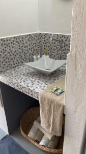 ein Bad mit einem Waschbecken und einem Korb unter einer Theke in der Unterkunft Studio Beira Mar in Imbituba