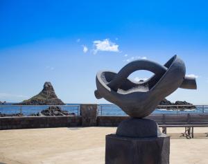 a statue in front of the ocean with a bench at Enjoy Home in Acitrezza