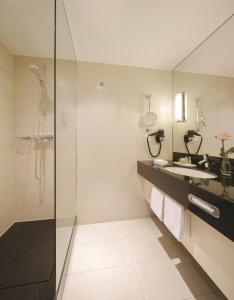 a bathroom with a glass shower and a sink at Mövenpick Hotel Egerkingen in Egerkingen