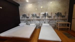 three beds in a room with palm trees on the wall at BALAN INTERNATIONAL lodging in Chennai